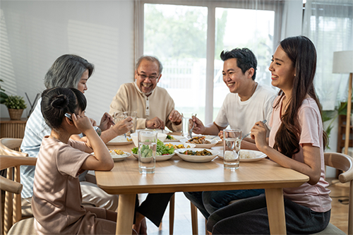Healthy multigenerational Asian family sits down to eat a meal together