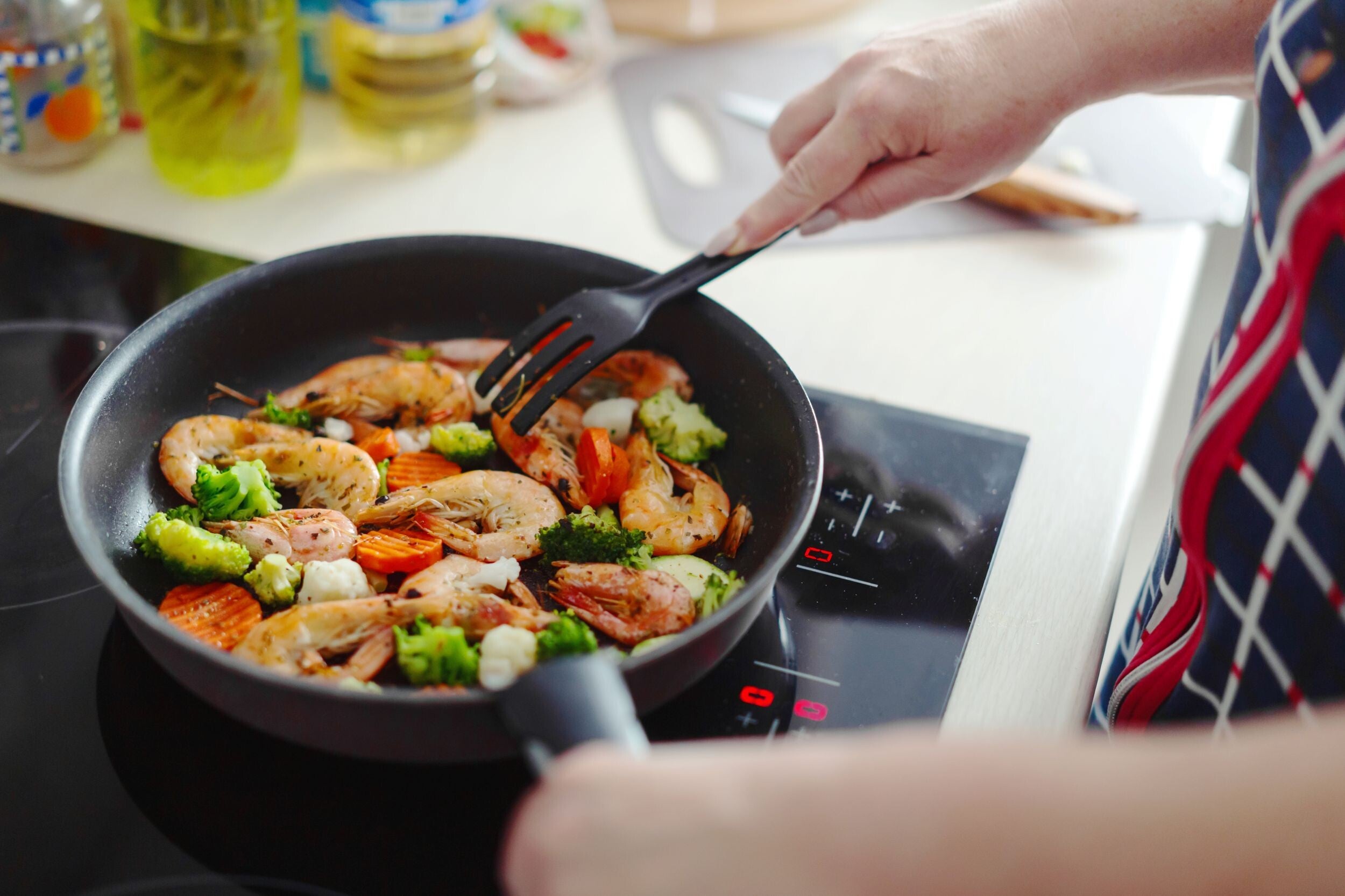 Close-up photo of iodine-rich food, shrimp with vegetables being cooked in a pan in the kitchen.
