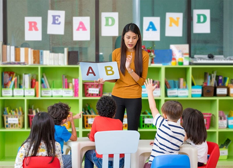 Kids in a kindergarten classroom listening to teacher
