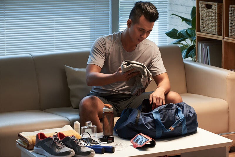 Man packing gym clothes into gym bag