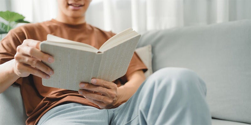 Man reading book on grey couch