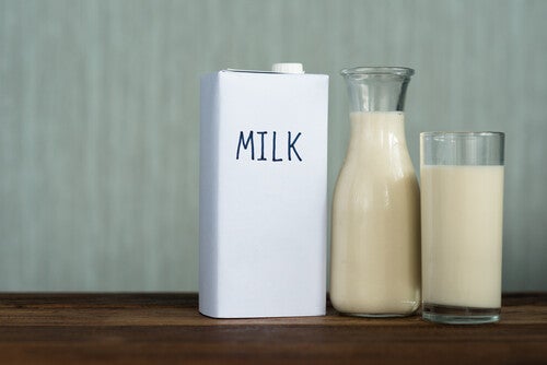 Milk in a carton, bottle, and glass on a wooden table