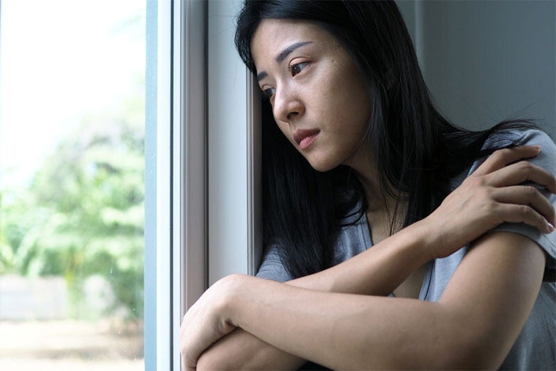 Mom looking outside the window suffering from postpartum blues