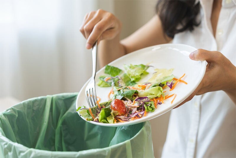 Mom throwing uneaten food into trash can