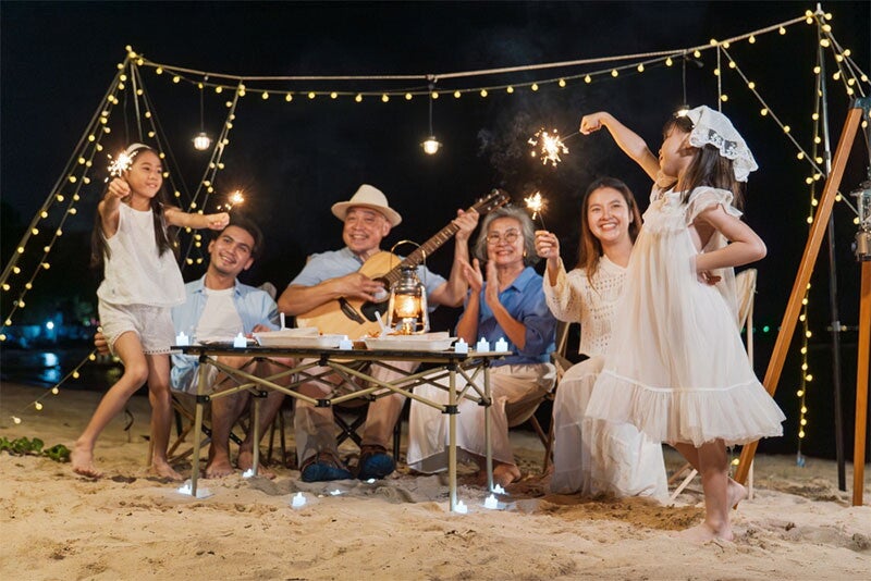 Multi-generation Asian family sing and dance during a beach vacation