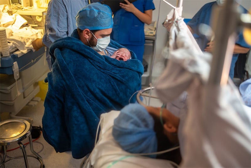 New dad performs skin-to-skin contact with his newborn in the delivery room.