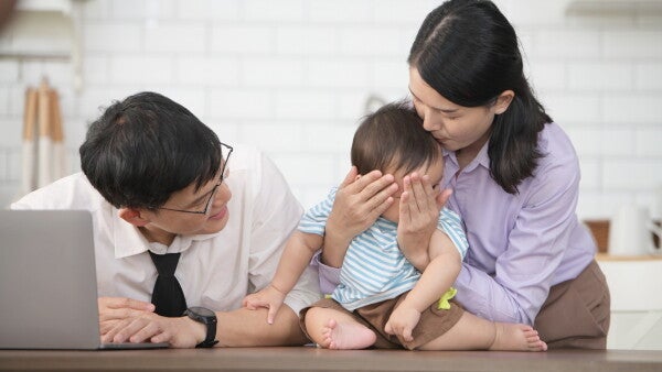 Parents play with their son after they come home from work.