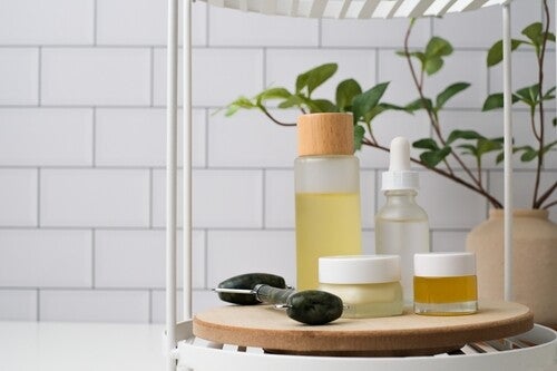 Photo of skin care products—natural oil, balm, serum, moisturizer, and a jade roller—on a caddy in the bathroom