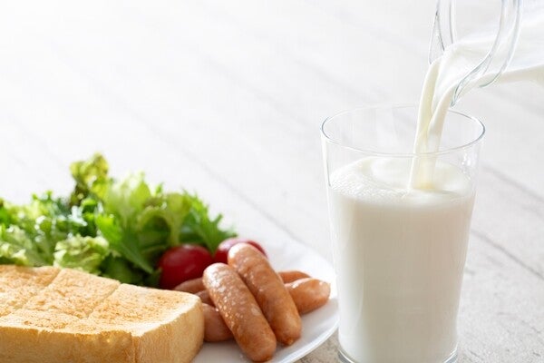 Photo of bottle of milk being poured into a glass with a nutritionally balanced meal beside it