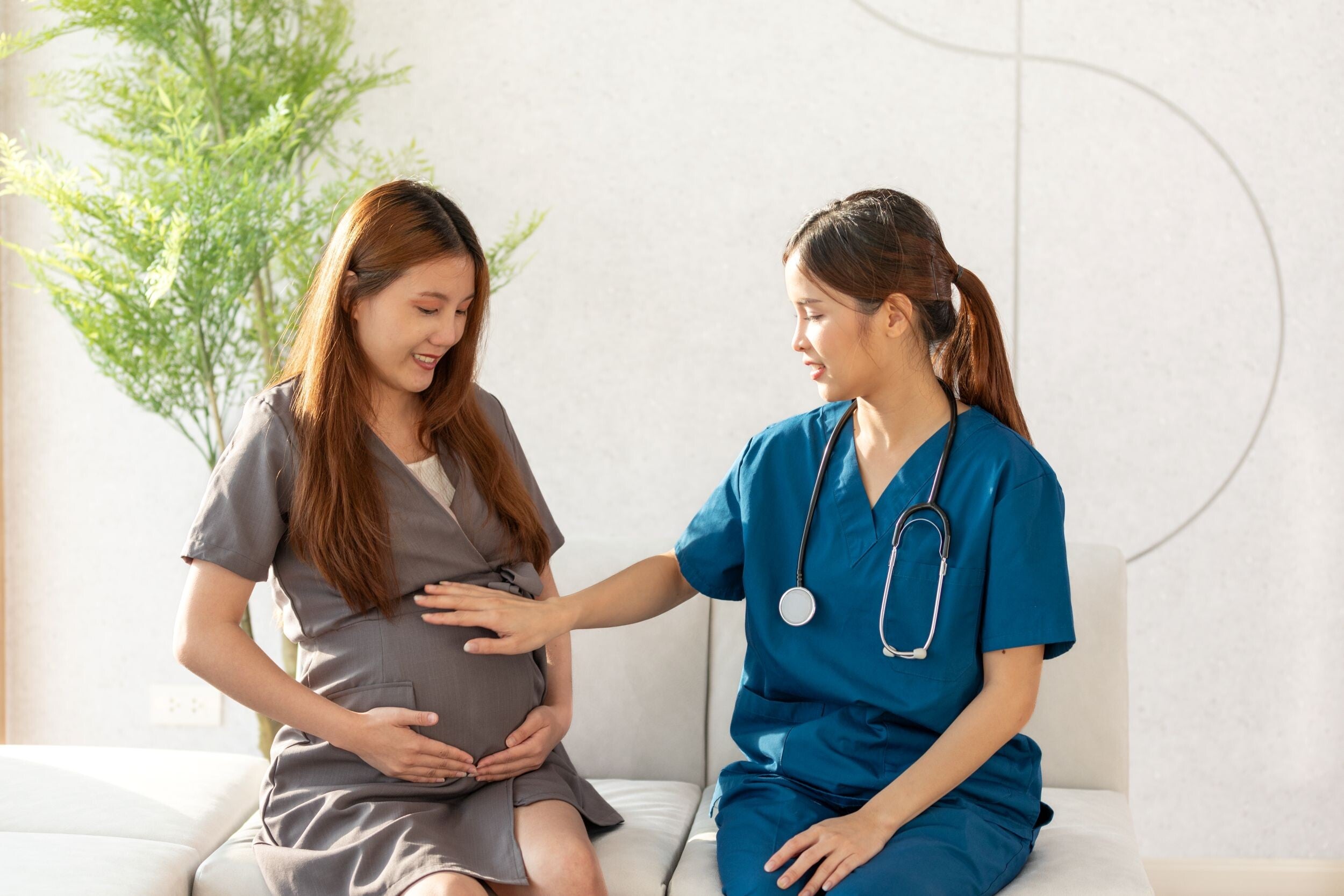 A pregnant Asian woman consulting with her doctor regarding nutrition.