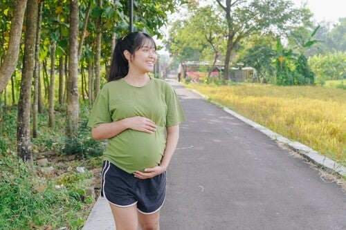 A young pregnant Asian woman walking outdoors as a form of light exercise
