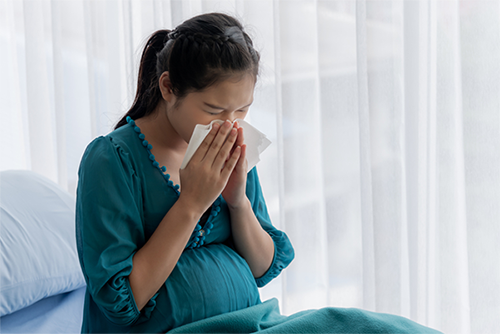 Pregnant Asian in a hospital bed suffering from the flu