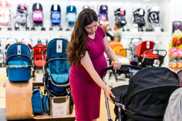 Pregnant Asian woman checks out a baby stroller while shopping at a mall