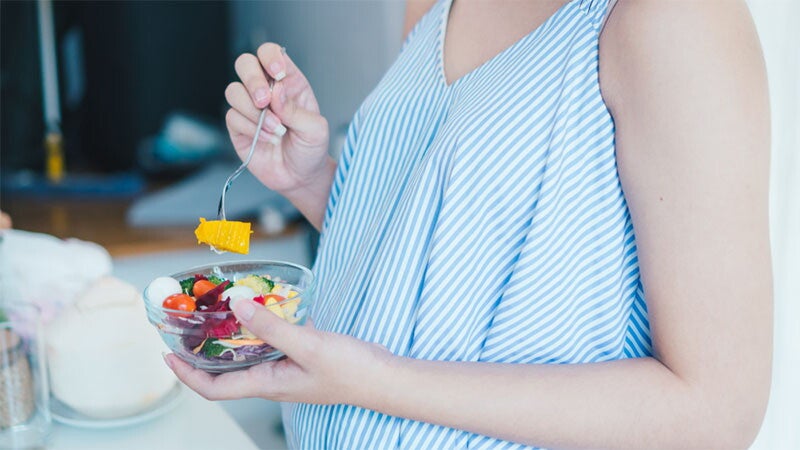 Pregnant woman eating a colorful salad