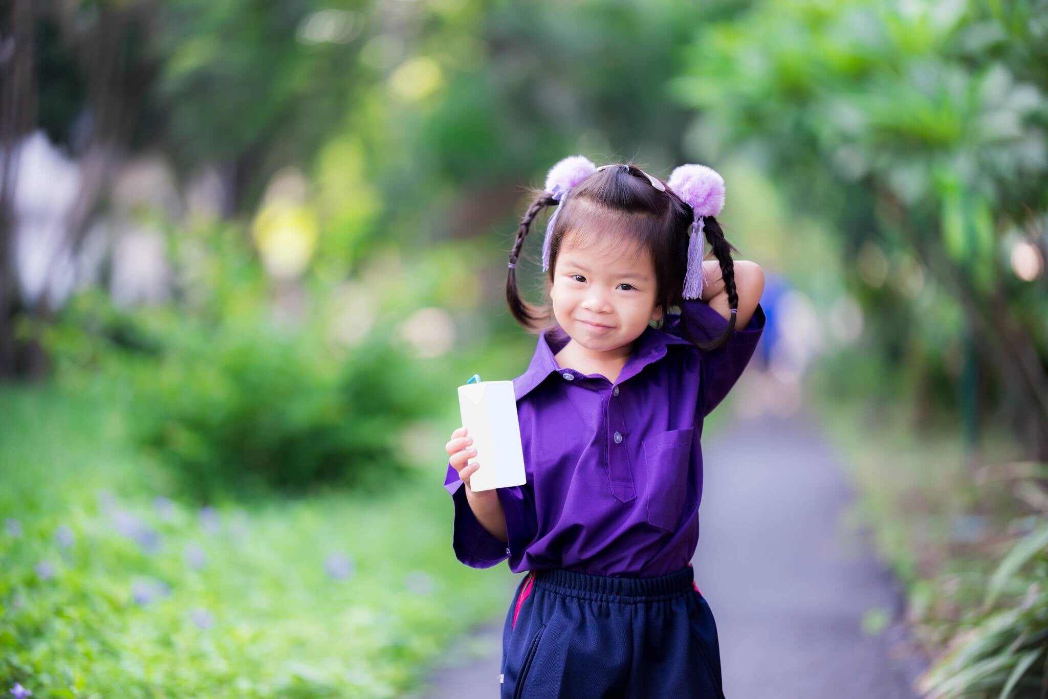 Little preschooler girl drinking a carton of sterilized milk during recess.