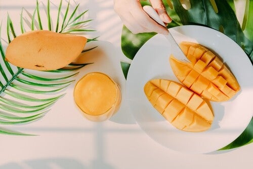 Ripe yellow mangoes on a plate and in a smoothie