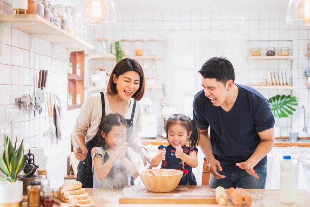 Family with two daughters cooking in kitchen.