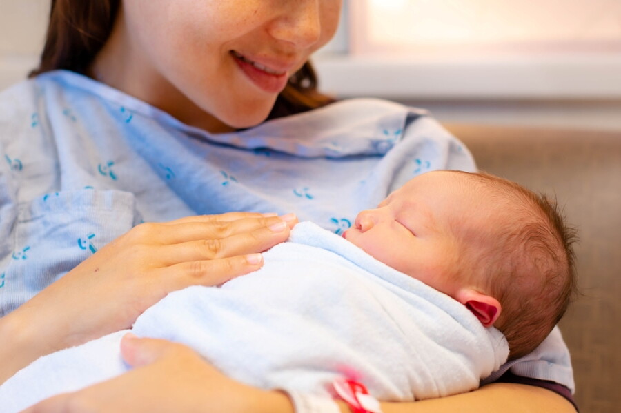 Happy Asian mother holding newborn.