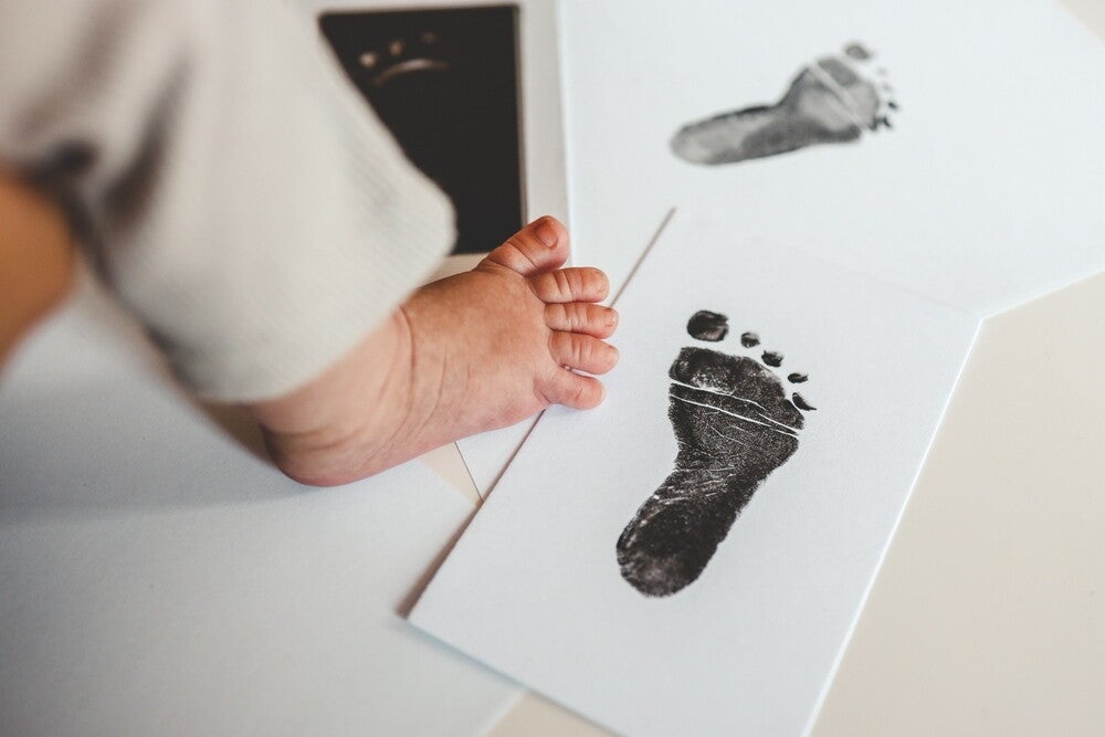 Baby footprints on white paper as baby monthly milestone idea.