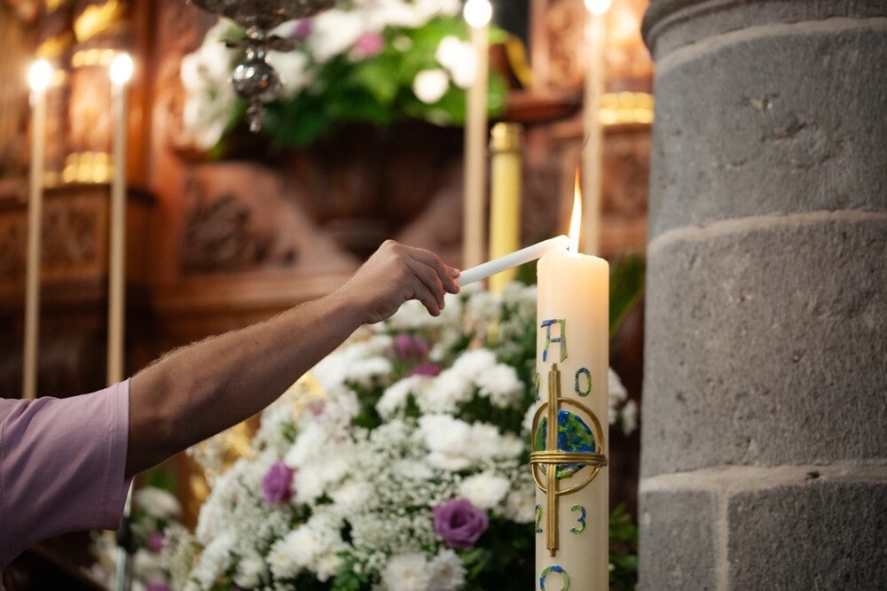 A hand lights a baptism candle at a Catholic Church.