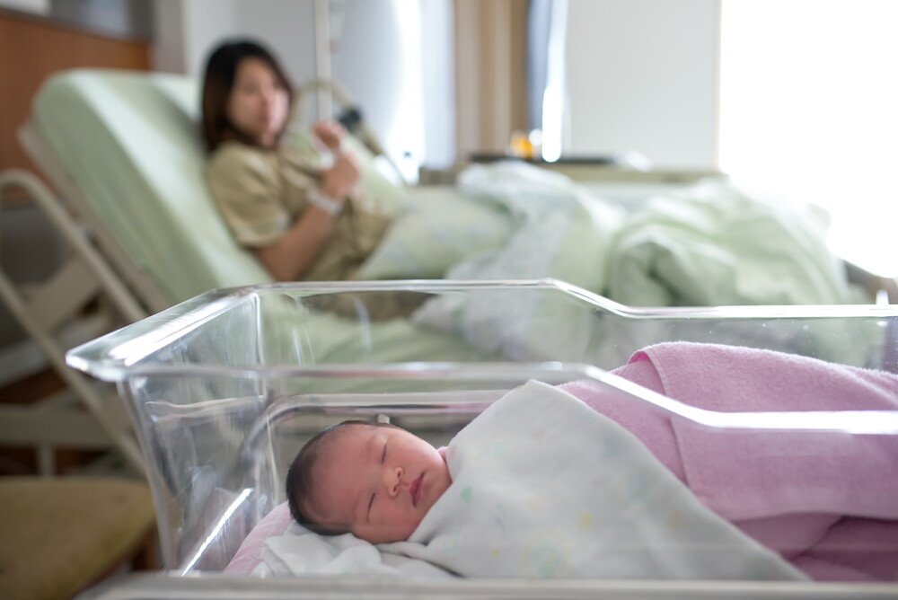 Sleeping newborn rooming in with mom at hospital.