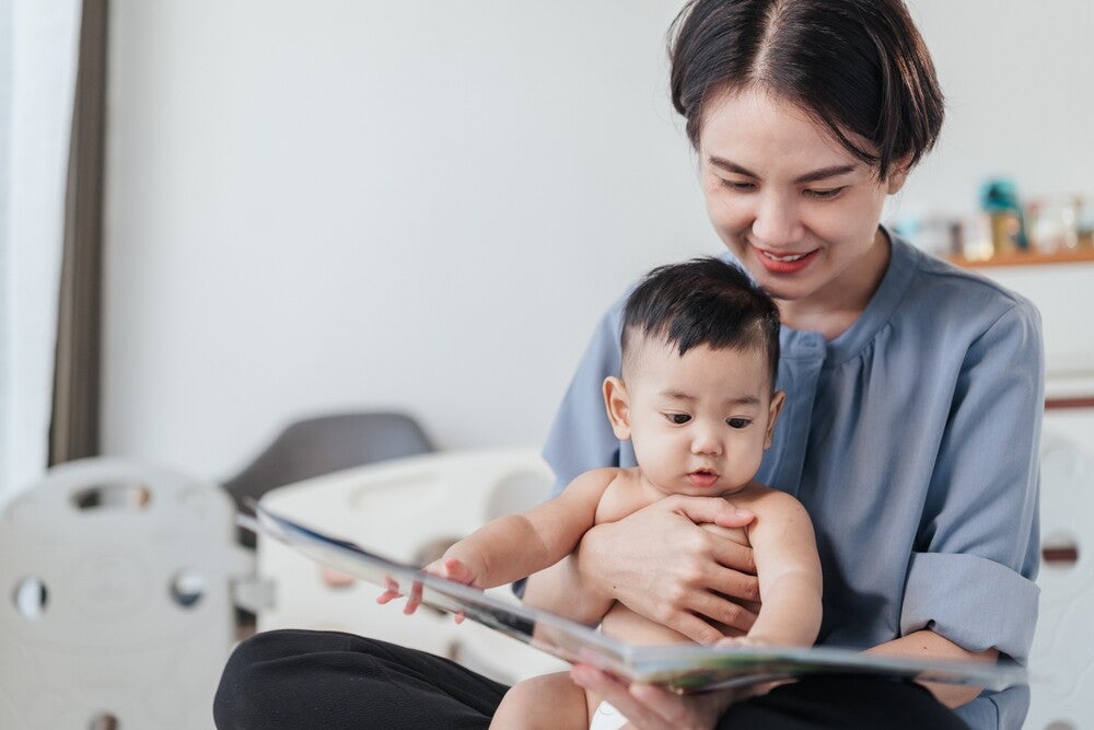 Asian mom reads to her baby boy to help with language development. 