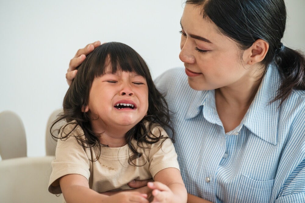 Asian mom comforts her toddler daughter to help develop emotional stability. 