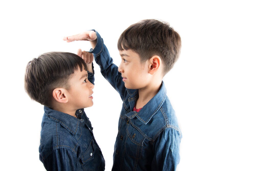 Two Asian boys compare each other's height. 