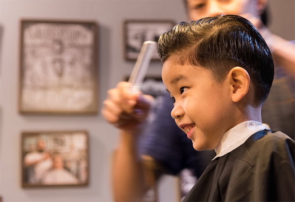 Smiling Asian little boy in a barbershop with a new haircut