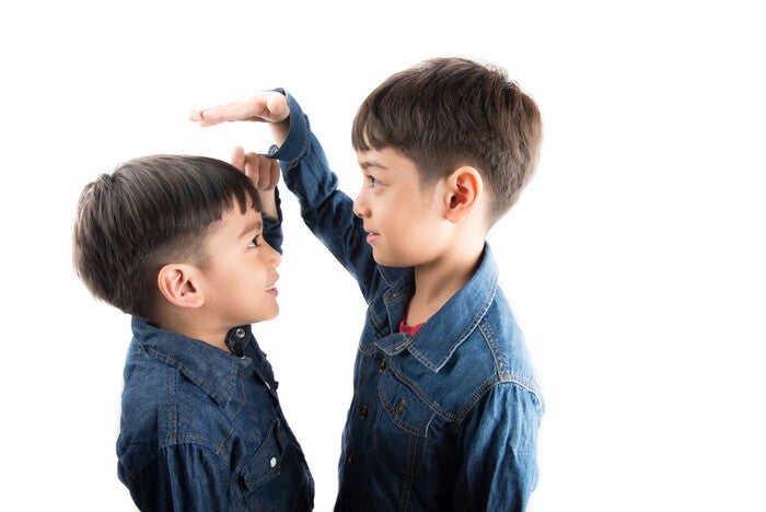 Two Asian boys compare each other's height.