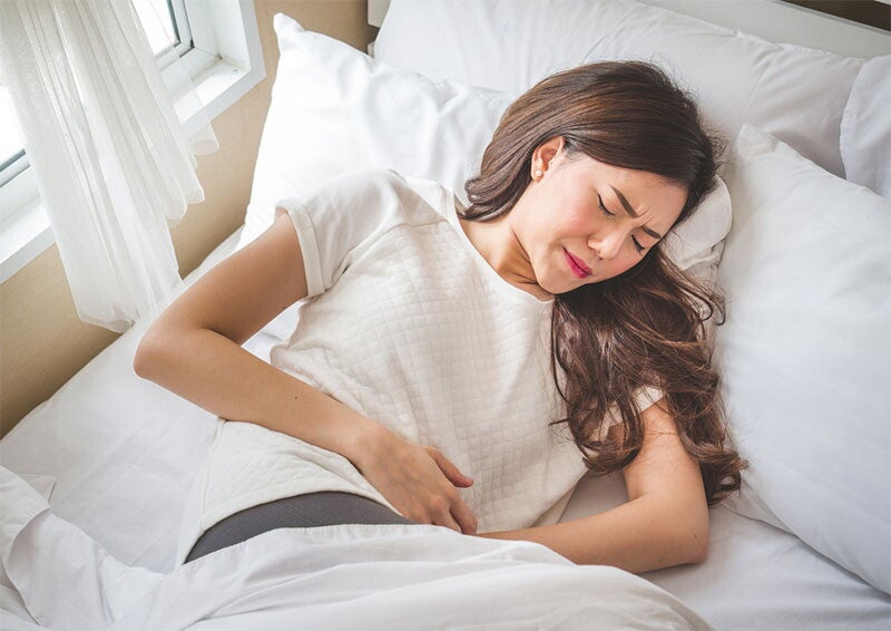 Woman lying in bed with cramps