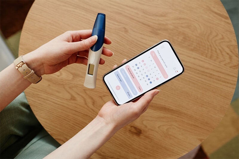 Woman using pregnancy kit and ovulation tracking app on a phone