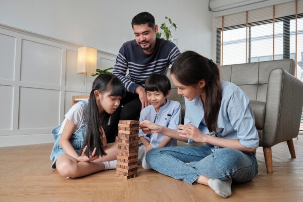 Asian family in blue playing tower blocks in the living room.