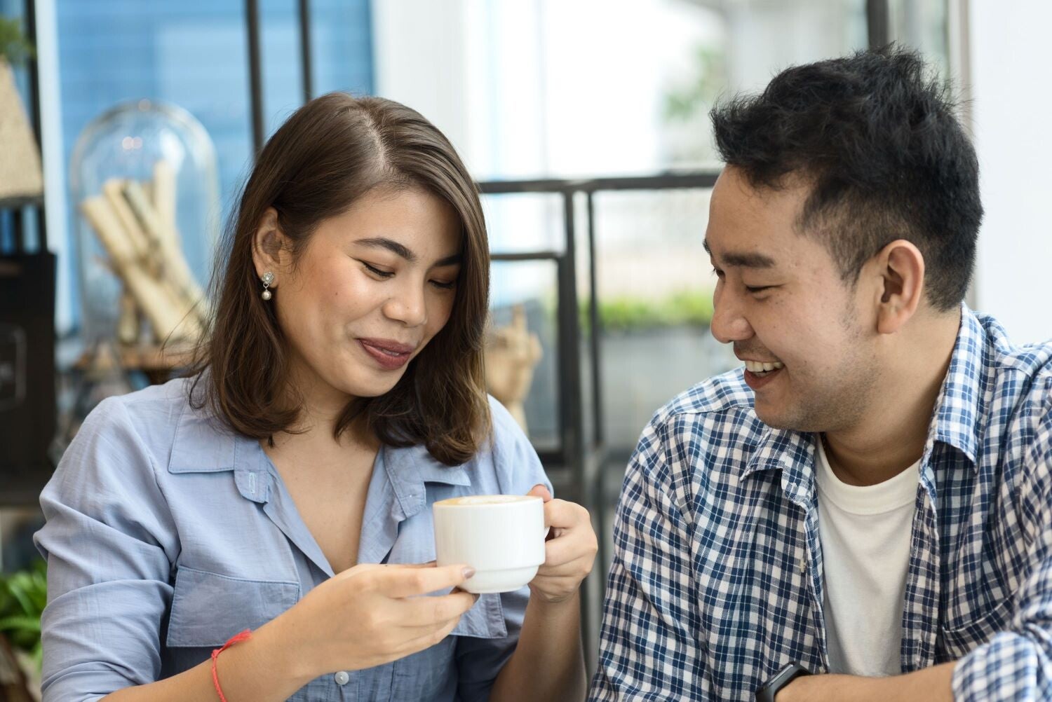 A young Asian man smiles at the single mom holding her coffee cup.