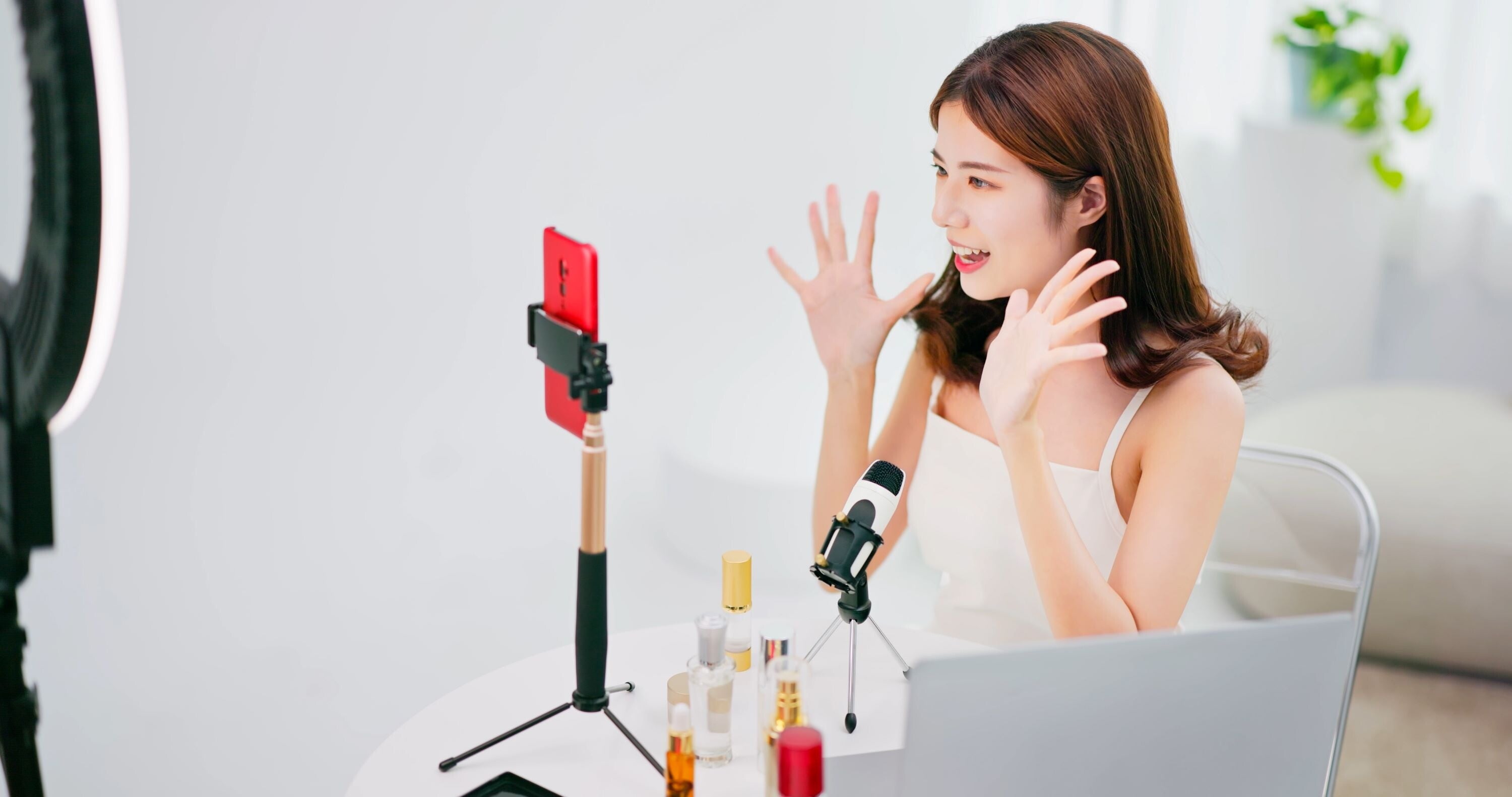 A young Asian woman filming herself with a ring light, reviewing scents at home for UGC on TikTok. 