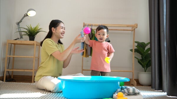 A young Asian woman playing with a toddler boy before bathtime.