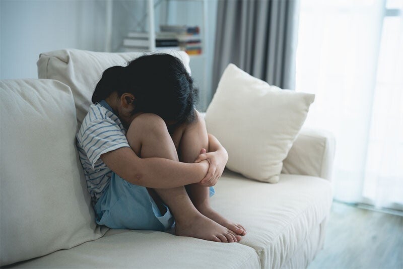 Young Asian girl sitting on couch during a time-out
