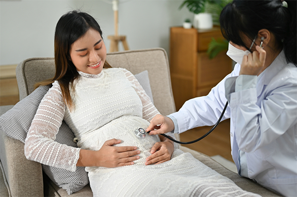Young pregnant Asian woman having a female doctor check her baby’s heartbeat in the womb.