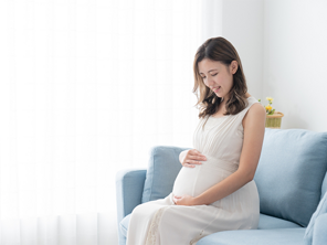 A 29 weeks pregnant Asian woman lovingly holding and looking at her belly at home A 29 weeks pregnant Asian woman lovingly holding and looking at her belly at home