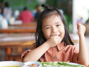 Preschooler picky eater Asian girl enjoying eating vegetables with her hands.