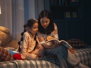 Asian mom and daughter reading a book at night as a daily routine.