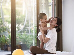 asian-mom-holding-baby-while-seated-on-floor