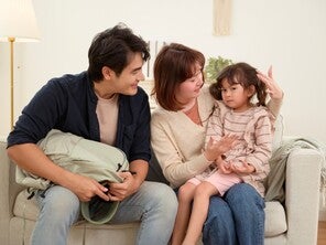 Asian parents at home in the living room talking to their child with social anxiety who doesn’t want to go to school.