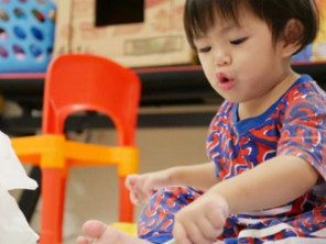 Asian 18-month-old baby scribbles with a pen during playtime.