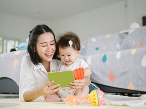Asian mom and toddler daughter happily reading