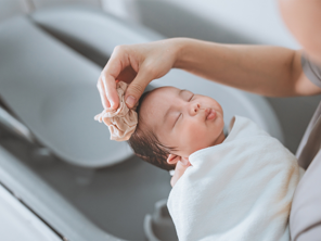 Asian mom washing newborn child in their baby bath.