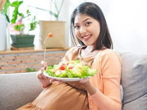Asian pregnant woman holds a plate of vegetable salad for her dailly vitamin intake. Asian pregnant woman holds a plate of vegetable salad for her dailly vitamin intake.