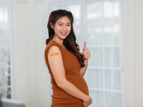 Asian pregnant woman performs a thumbs-up sign after getting vaccine for pregnant women.