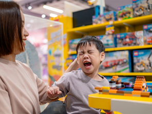 Asian toddler becomes short-tempered while in a toy store with mom Asian toddler becomes short-tempered while in a toy store with mom