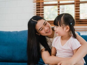 Asian woman sits her child on her lap and looks at her lovingly after she had to discipline her